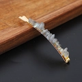 Detail of gold bobby pin with grey-blue natural crystal stones on a wooden tray - Grey Flash Labradorite Gold