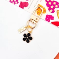 Floral metal keychain with black enamel flower and handmade tag on white background - Black