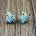 Macro detail of raw light blue stone stud earrings with a four-prong gold metal setting - Amazonite