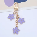 Detail of a gold-tone keychain featuring three purple enamel flowers and a D-ring clasp - Purple