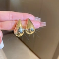 Macro shot of polished gold-plated teardrop earrings with a mirror finish - Gold