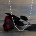 Élégant collier de perles blanches sur chaîne dorée avec fond de roses rouges - Type standard