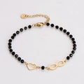 Dettaglio del bracciale di perline nere con ciondoli a cuore e infinito color oro - Stile Cuore Cavo + Infinito
