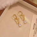 Boucles d'oreilles papillon dorées avec zircon et pendentifs goutte d'eau sur écrin velours - Blanc