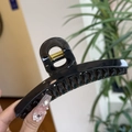 Close-up of a large black glossy hair claw clip with a strong golden metal spring - Transparent Black