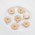 Macro view of 7 pieces of enamel daisy charms with gold borders and metal backs - White