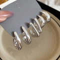 Macro view of three pairs of silver mirror-polished wide hoop earrings on a display card - Silver Needle - Silver (6-Piece Set)