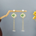 Detail of long gold tassel earrings with bamboo pattern and white pearls on wooden branch - Gold Cloud Enamel Bamboo Tassel Earrings(E5207)