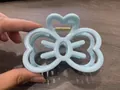 Sky blue bow-shaped hair claw clip with heart detail held in hand on dark wood background - Sky Blue