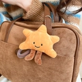 Dettaglio di un ciondolo a stella in peluche giallo con faccina appeso a una borsa marrone - Stile Stella Gialla