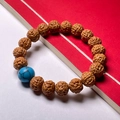Close-up of brown Rudraksha bodhi seed bracelet featuring a vibrant blue turquoise bead - Toad Back 8-10mm (Turquoise Bead)