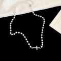 Dettaglio della collana di perle con ciondolo a croce d'argento su sfondo nero liscio - Argento
