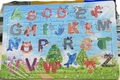 Alphabet puzzle board with 26 colorful wooden letters featuring cute cartoon animal designs - Alphabet Cognition