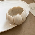 Detail of beige marble resin bracelet with petal shaped modules on ceramic plate - White-Square