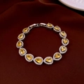 Detailaufnahme eines Tennisarmbands mit gelben Edelsteinen auf dunklem Seidenhintergrund - Silber-Gelb (Birnenform Halo)