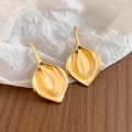 Detailed view of polished gold leaf earrings on white textured paper and wood - Gold (Silver Earring Post)