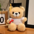 Plush graduation teddy bear with black mortarboard and diploma roll on a desk - White T-Shirt Style / Tan