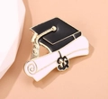 Graduation brooch with black mortarboard and white diploma scroll in golden finish - Cap and Diploma Combo Style (SXZ364)