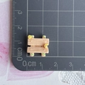 Detailed macro view of miniature dollhouse resin stool on a grey grid cutting mat - Wooden Chair with Vine Flowers