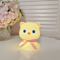 Close-up of a glowing cat night light with a red bow tie in a cozy home setting - Nini Cat - Pink