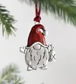 Macro detail of Christmas gnome pendant with red enamel hat and lantern on pine branch - Gnome
