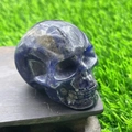 Detailed 5cm dark blue crystal skull gemstone carving on a rustic wooden base - Blue Sodalite