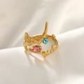 Detail view of a hammered gold open ring featuring textured vines with blue and pink gems - AB Zirconia Ring / Gold