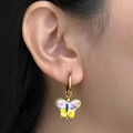 Detailed macro view of colorful enamel butterfly pendant hanging on a gold hoop earring - Colorful Butterfly