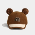 Détail d'une casquette bébé avec oreilles en peluche, bord en velours et logo M 3D - Lettre M / café