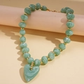 Detail of green marbled acrylic heart pendant and gold beads on a sweater chain - Necklace / Green