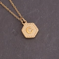 Detail macro-opname van een zeshoekige gouden hanger met letter C en een gehamerde textuur - Letter C (3#C)