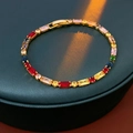Primer plano de pulsera bañada en oro con circonitas de colores en soporte verde - Pulsera de Circonitas Rectangulares de Colores Chapada en Oro (Estilo 1) / Dorado