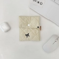 Detail of beige quilted makeup bag with black bow embroidery and secure snap button - Sanitary Pouch