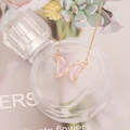 Close-up of a pink butterfly crystal pendant with small diamonds on a gold chain - Pink
