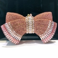 Close-up of pink bow-shaped evening clutch bag with sparkling rhinestones and gold hardware - Pink