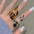 Detail of irregular geometric acrylic rings with brown tortoiseshell patterns on a hand - Mixed Dark Brown and Light Beige