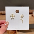 Asymmetric gold floral studs with white enamel petals on a jewelry display card - White Flower Branch (Silver Post) (2641)