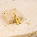 Minimalist gold-plated letter H pendant necklace displayed on natural beige stone - Letter-H / Gold