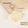 Realistic white PVC dumpling keychain with metal ring on a textured wood background - White Original Dumpling - Keychain Style