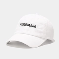 Detailed close-up of white cotton baseball cap with black Founded 1986 embroidery - Adjustable / White
