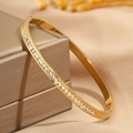 Macro shot of gold stainless steel bangle with square zircon inlay on champagne jewelry box - Single Row / Gold