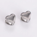 Macro detail of silver heart hoop earrings featuring a polished vertical striped texture - Steel