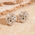 Vue macro de boucles d'oreilles rondes en métal argenté avec texture géométrique - Carré Argent