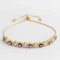 Dettaglio del bracciale occhio di Allah regolabile con zirconi su sfondo in pelle bianca - Nero