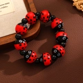 Détail d'un bracelet en perles avec motifs de coccinelles rouges et perles noires brillantes - Motif Coccinelle (Rouge)