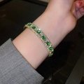 Makroaufnahme des vergoldeten Armbands mit grünen Zirkonen und Pavé-Kristallen - Pavé-Armreif / Silber Grüner Quadratischer Zirkon