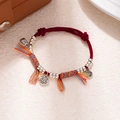 Detailed shot of handmade red rope bracelet featuring a silver Fu pendant and tassels - L312-5 Peace and Fortune