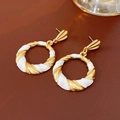 Detailed shot of vintage gold twisted hoop earrings with white enamel on leather surface - 71# Silver Pin Enamel Twist Cross Circle Stud Earrings Variant