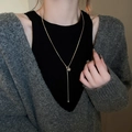 Détail d'un long collier en Y doré avec pendentif carré en zircon sur un pull gris - Style Carré Zircone n°3 / Doré