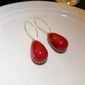 Elegant red teardrop earrings with gold hooks on a minimalist white ceramic tray - Ear Hook Style 2